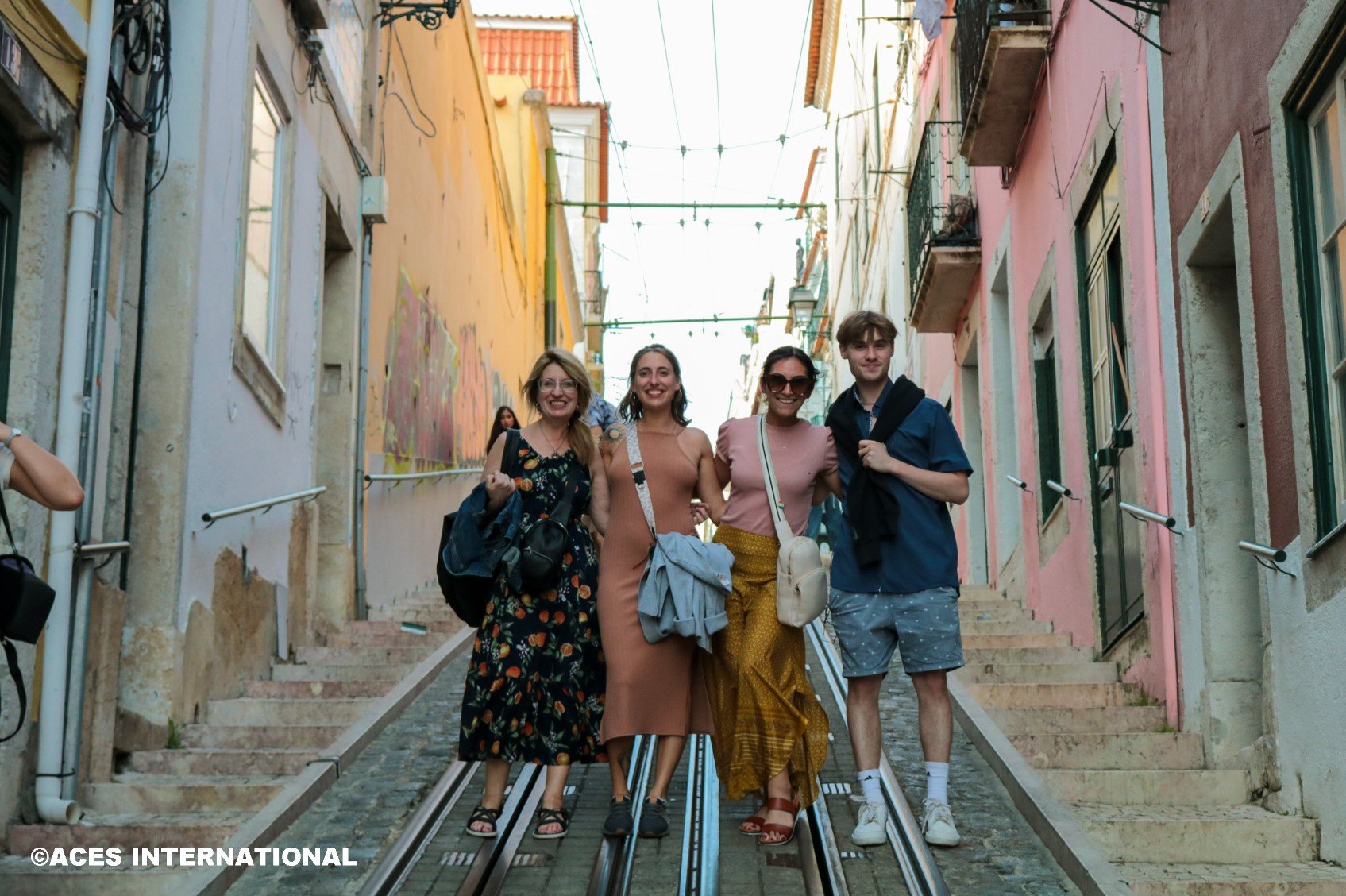 Four Educators Field Study group members take a picture in front of trolley train rails in Portugal.